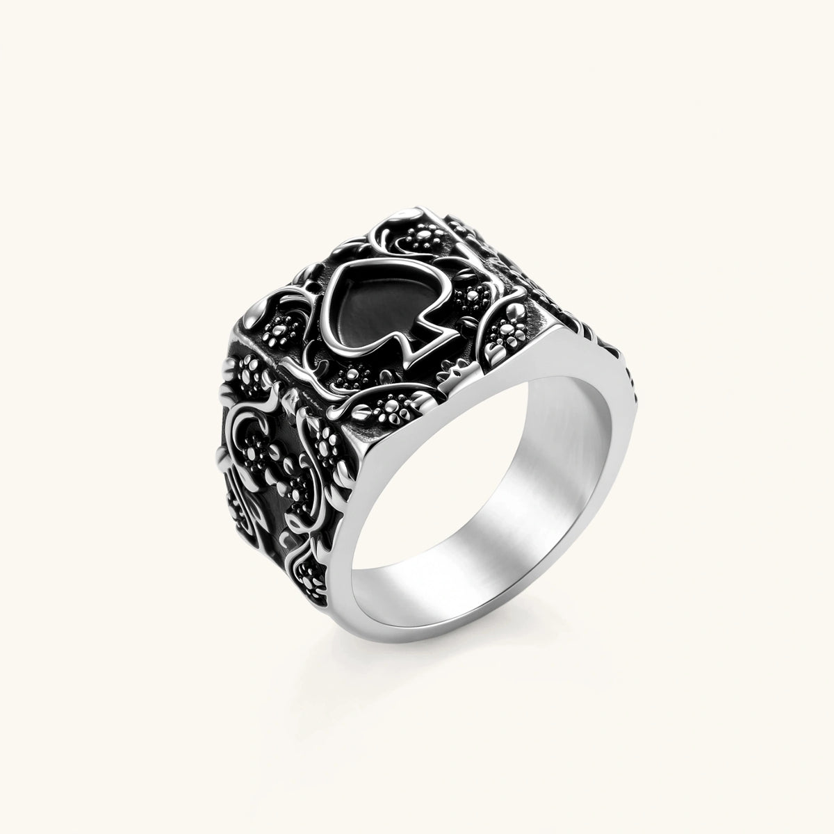 Silver-tone 316L stainless steel signet ring with black enamel spade motif and intricate floral scrollwork relief detail.