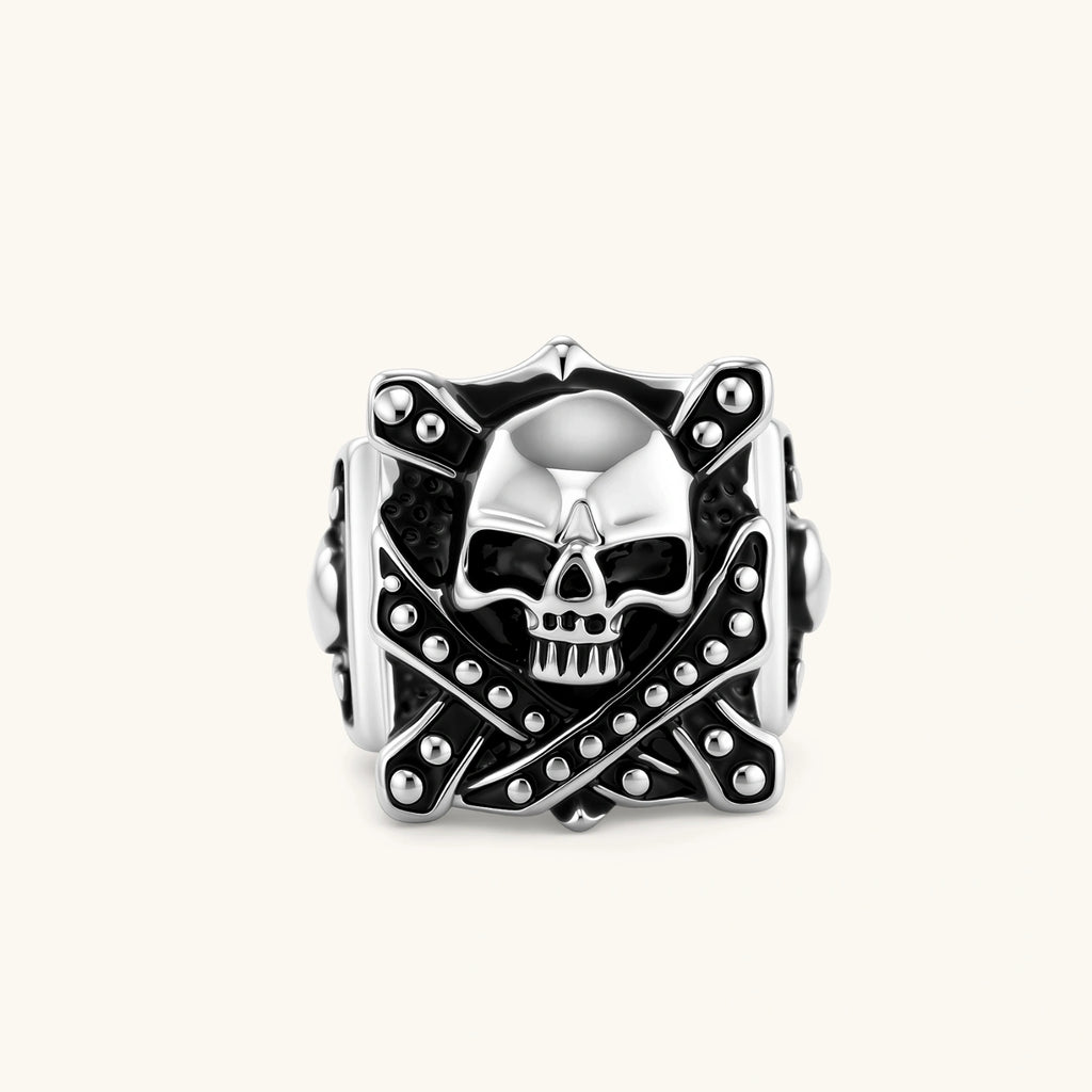 Silver-tone 316L stainless steel skull ring with crossbones, black enamel fill, studded details, and wide shank, 21mm top width.