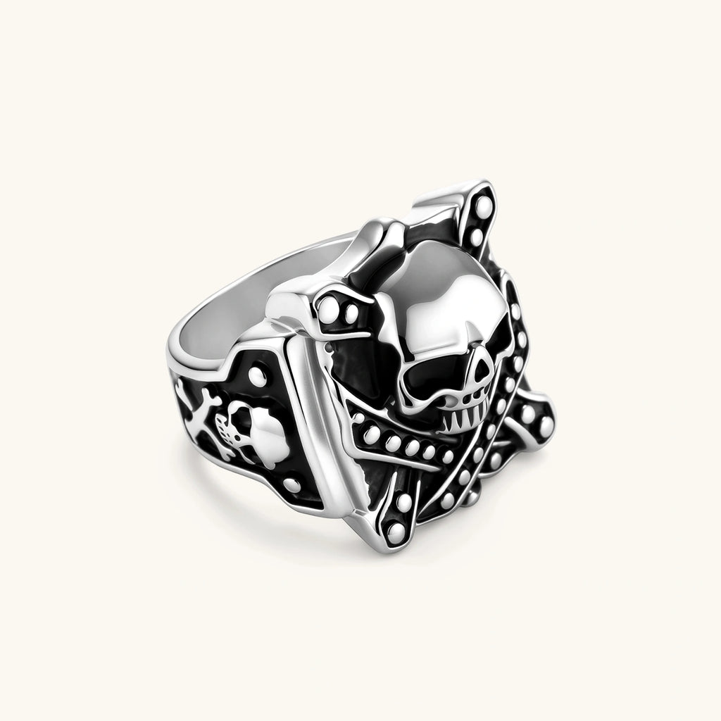 Silver-tone 316L stainless steel skull ring with crossbones, black enamel fill, studded details, and wide shank, 21mm top width.