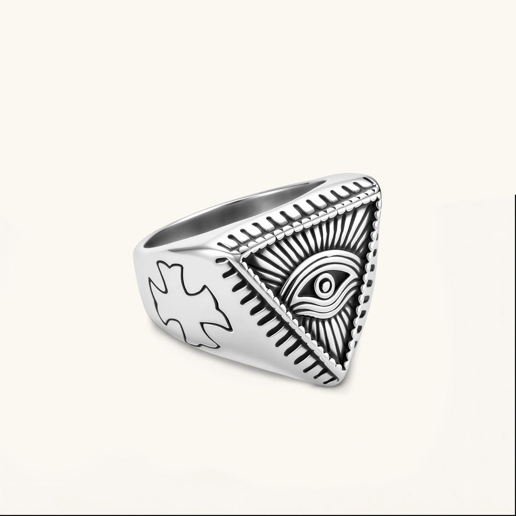 Silver stainless steel signet ring with engraved all-seeing eye in triangle, radiating lines, and cross motifs on the band.