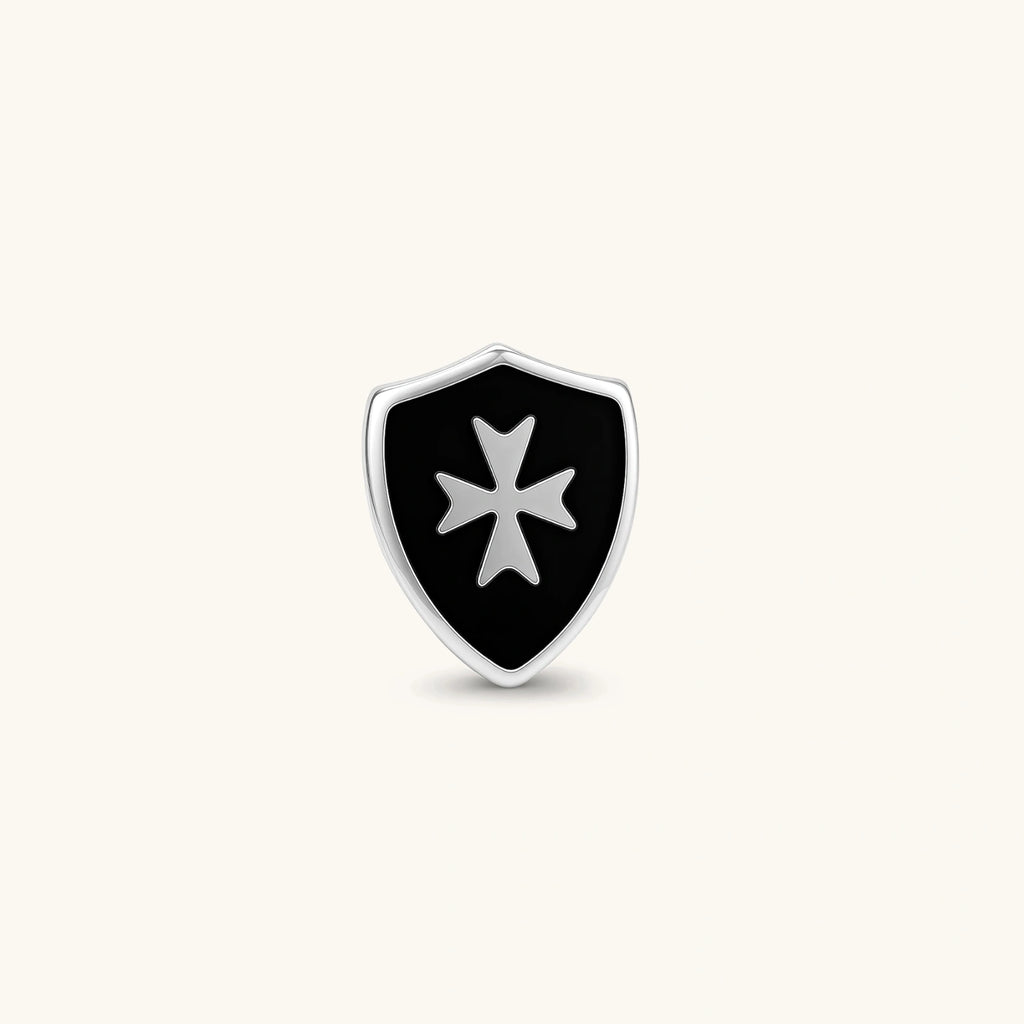 Silver stainless steel shield-shaped stud earring with black enamel and raised Maltese cross, rubber-secured backing.