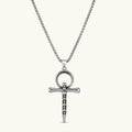Silver stainless steel ankh pendant with skull motifs on vertical bar and textured ring top, on a box chain necklace.