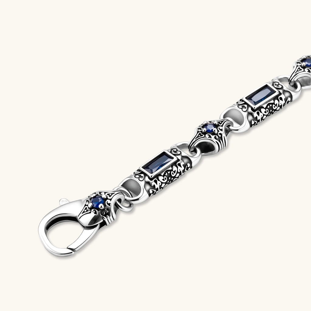 Oxidized silver stainless steel link bracelet with baguette blue CZ stones and intricate scroll engravings, lobster clasp.
