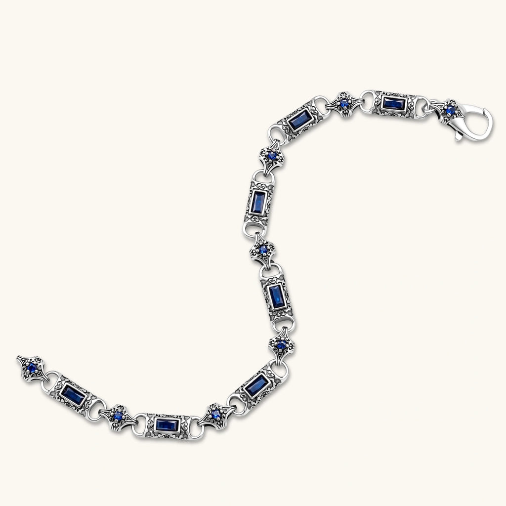 Oxidized silver stainless steel link bracelet with baguette blue CZ stones and intricate scroll engravings, lobster clasp.