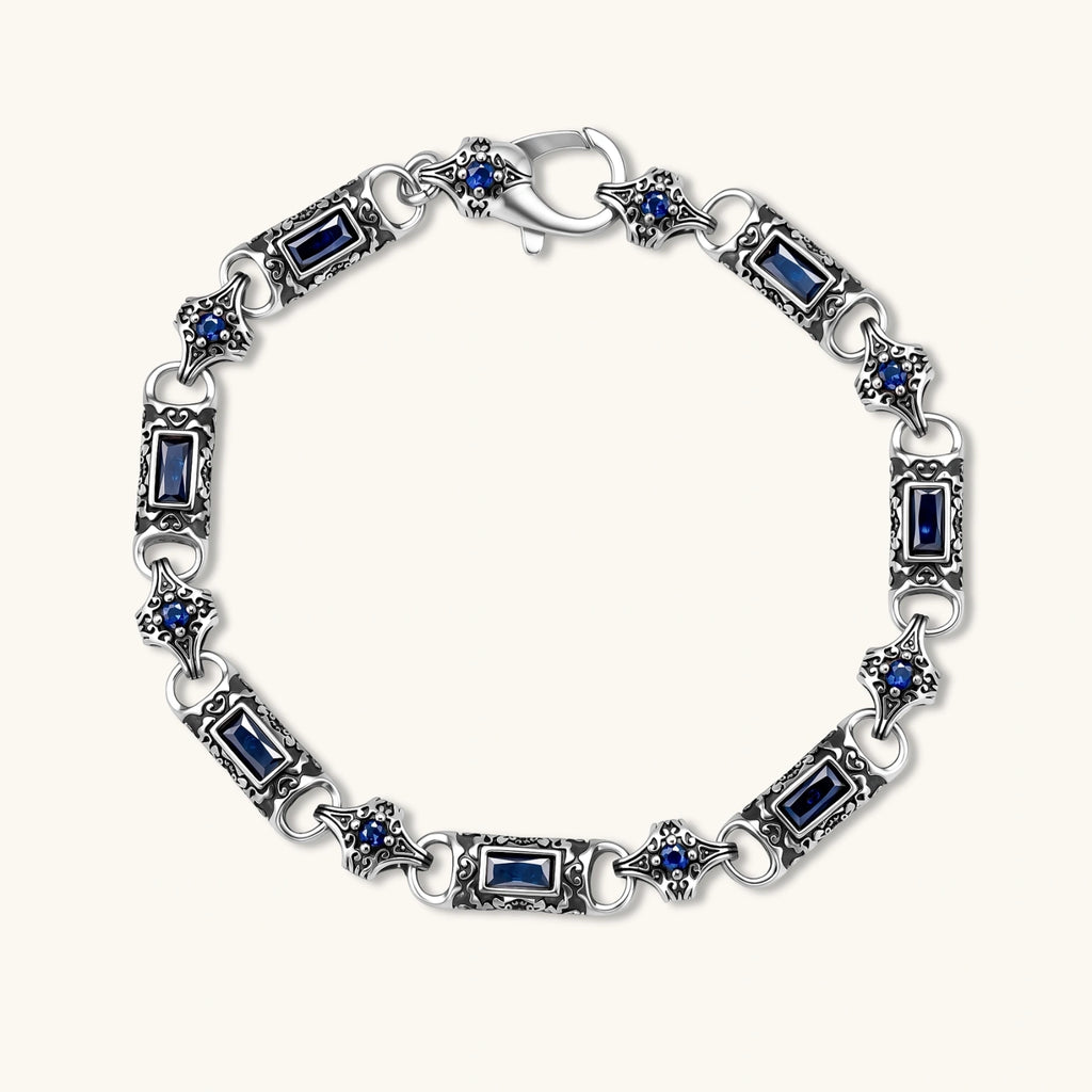 Oxidized silver stainless steel link bracelet with baguette blue CZ stones and intricate scroll engravings, lobster clasp.