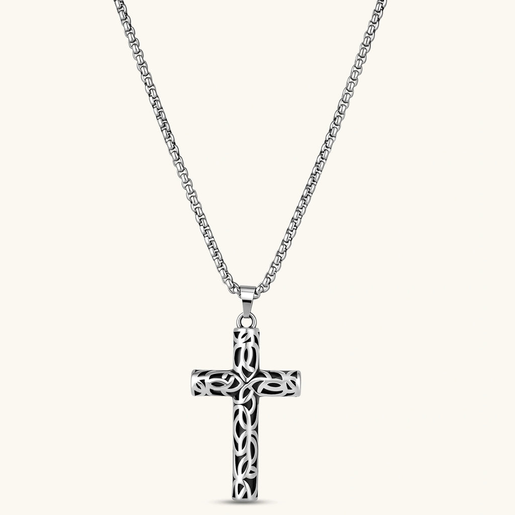 Silver stainless steel Celtic cross pendant with filigree vine pattern on a box chain, against a cream background.