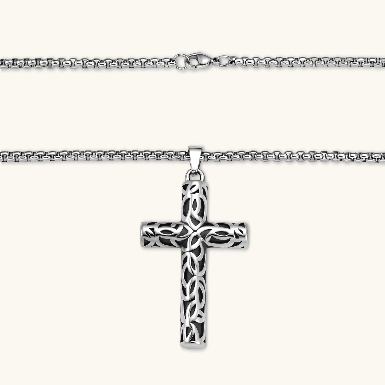 Silver stainless steel Celtic cross pendant with filigree vine pattern on a box chain, against a cream background.