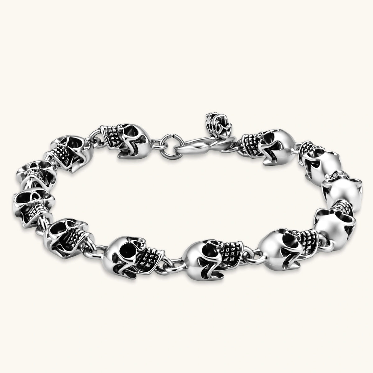 Silver stainless steel bracelet with linked 3D skull charms and a spring-ring clasp, oxidized black detailing, 225mm length.
