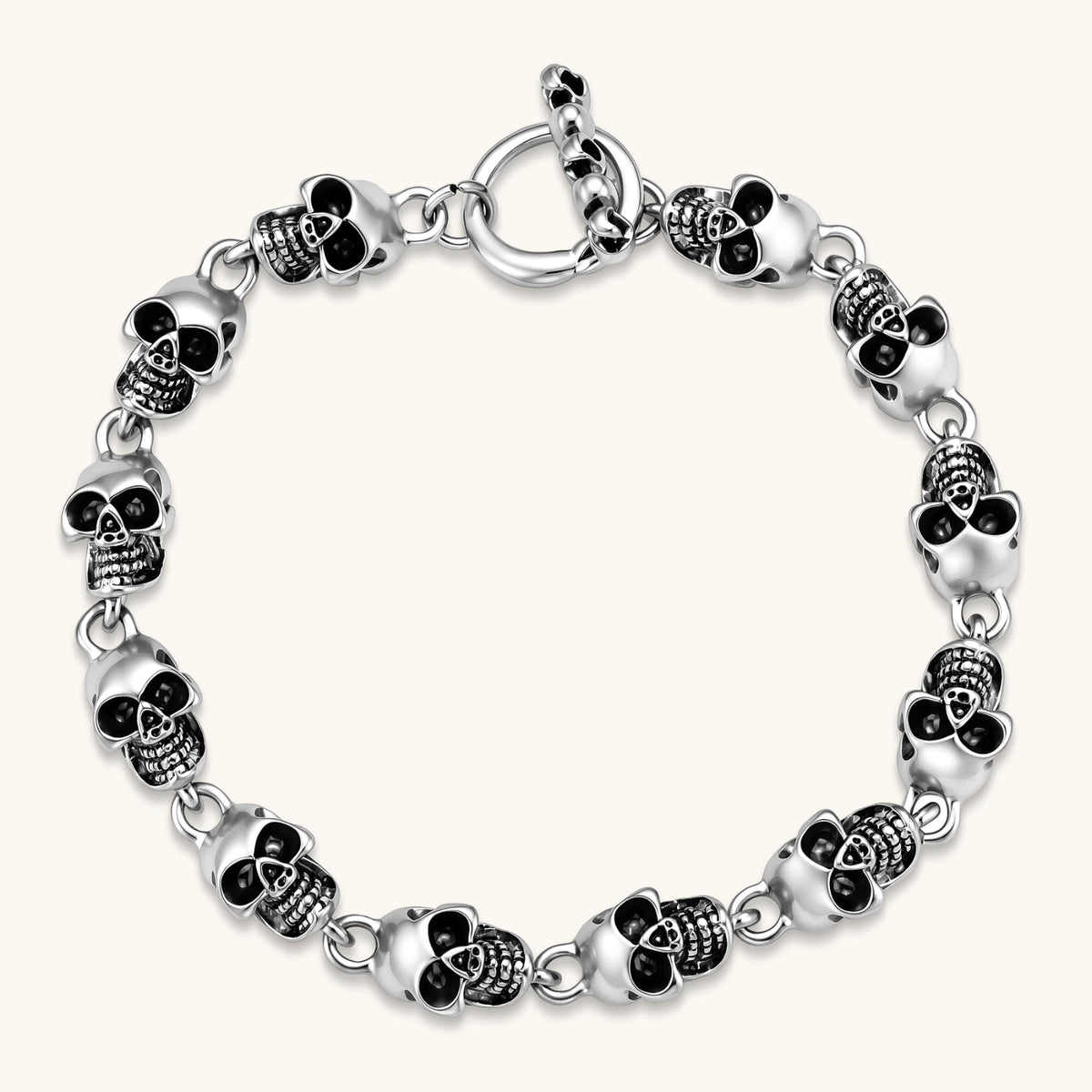 Silver stainless steel bracelet with linked 3D skull charms and a spring-ring clasp, oxidized black detailing, 225mm length.