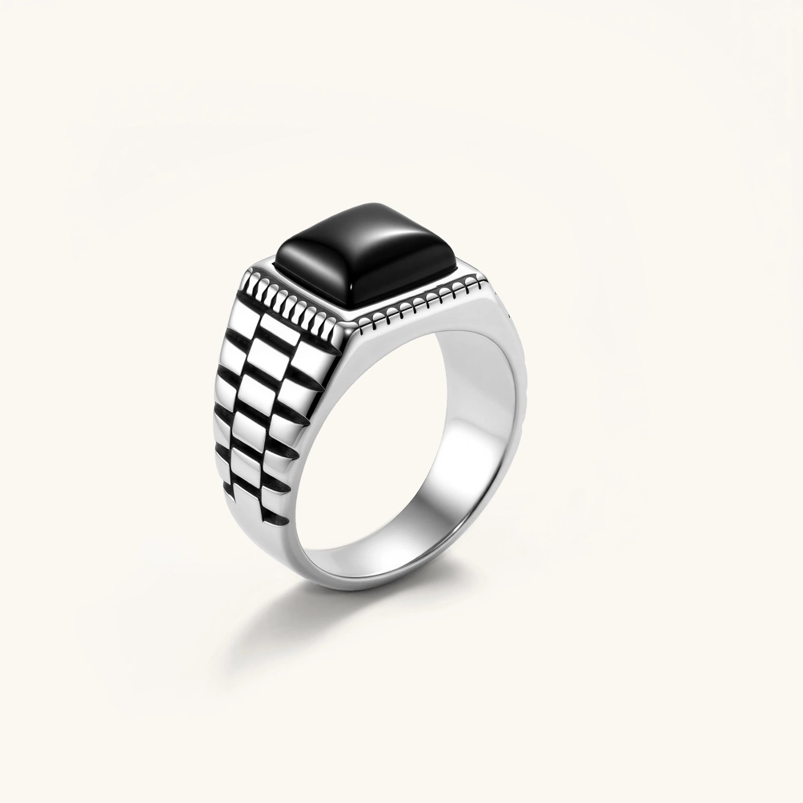Silver stainless steel signet ring with checkered band texture, beaded border, and square black onyx cabochon stone center.