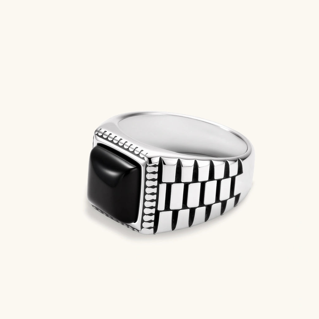 Silver stainless steel signet ring with checkered band texture, beaded border, and square black onyx cabochon stone center.